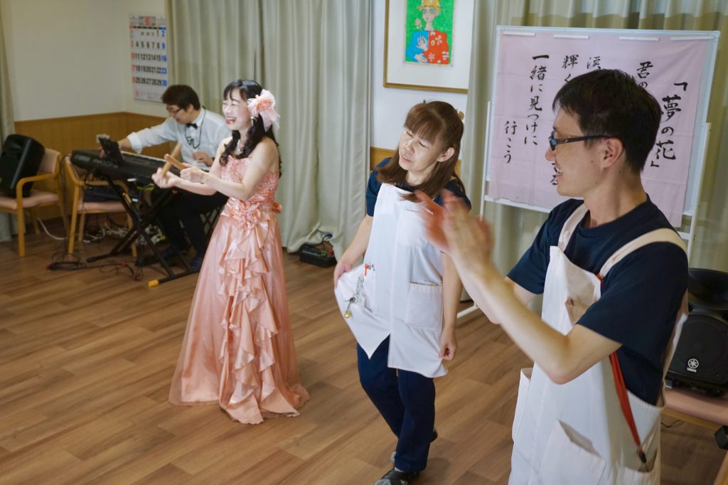 歌うメンバーと踊るスタッフ